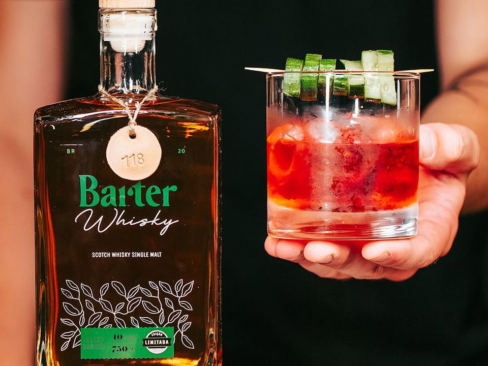 Garrafa de Barter Whisky ao lado de um drink servido no bar