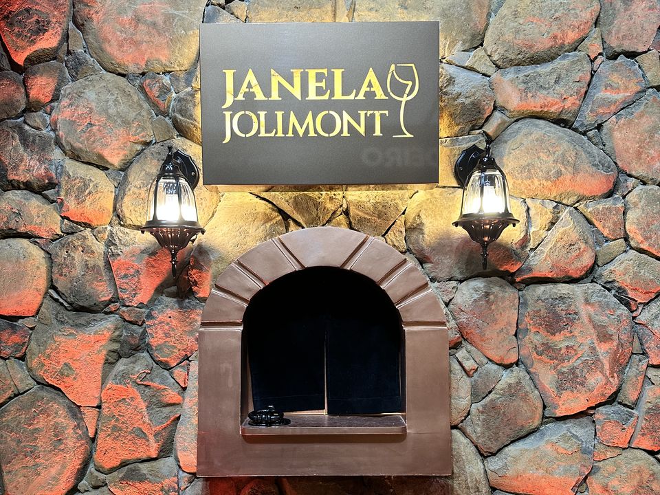 Janela em arco na parede de pedra com o letreiro Janela Jolimont e dois lampiões