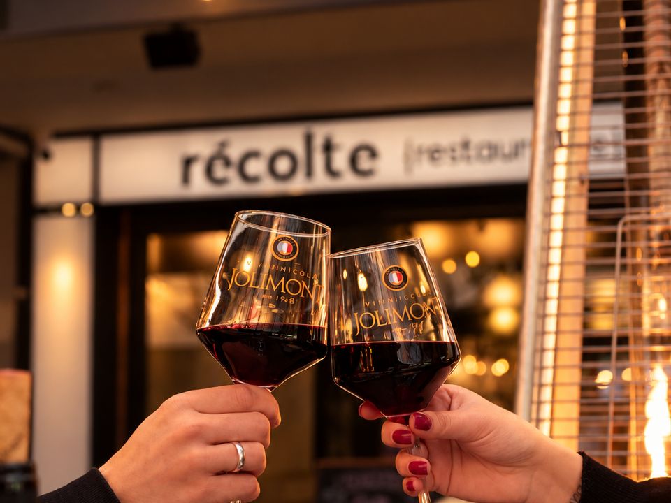 Brinde com duas taças de vinho Jolimont em frente ao letreiro do Récolte